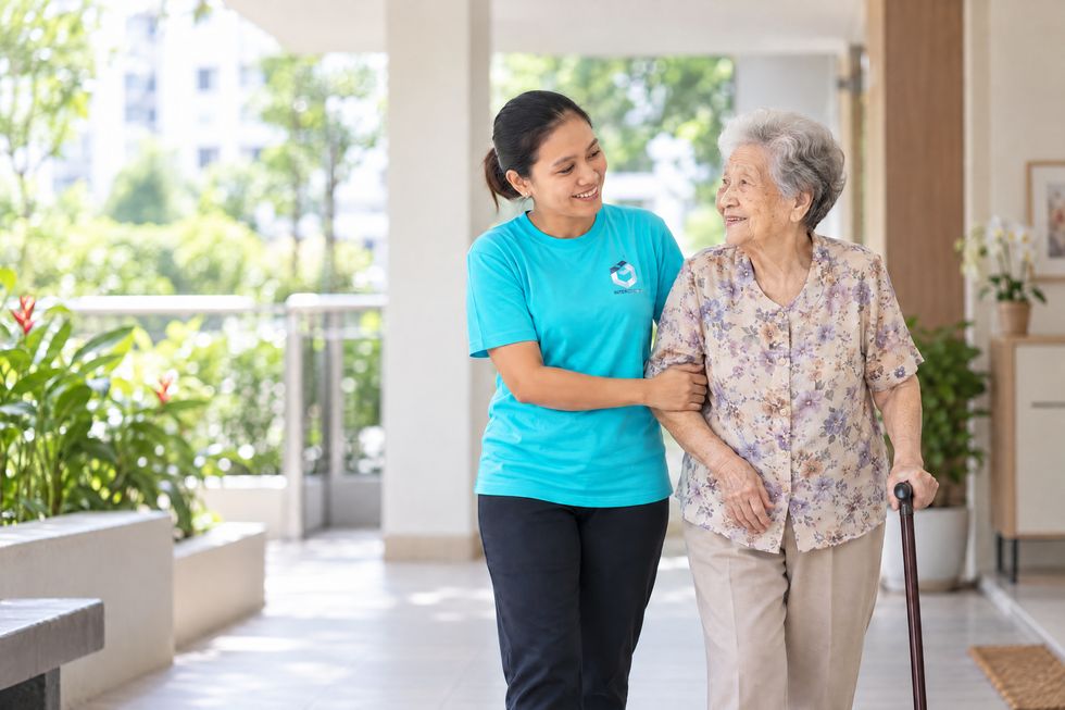 INTERGREAT helper walking arm in arm with an elderly woman